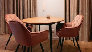 Un comedor con una mesa redonda y cuatro sillas, una vela y una lámpara colgante moderna.