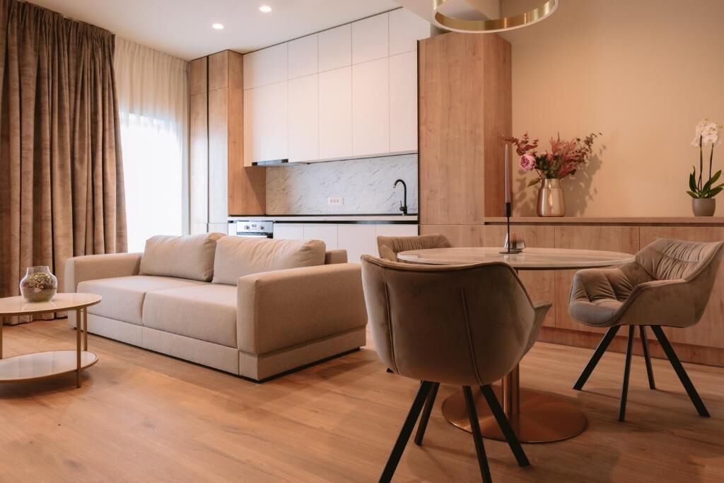A modern living room with a sofa, a round coffee table, and a dining area with a chair.