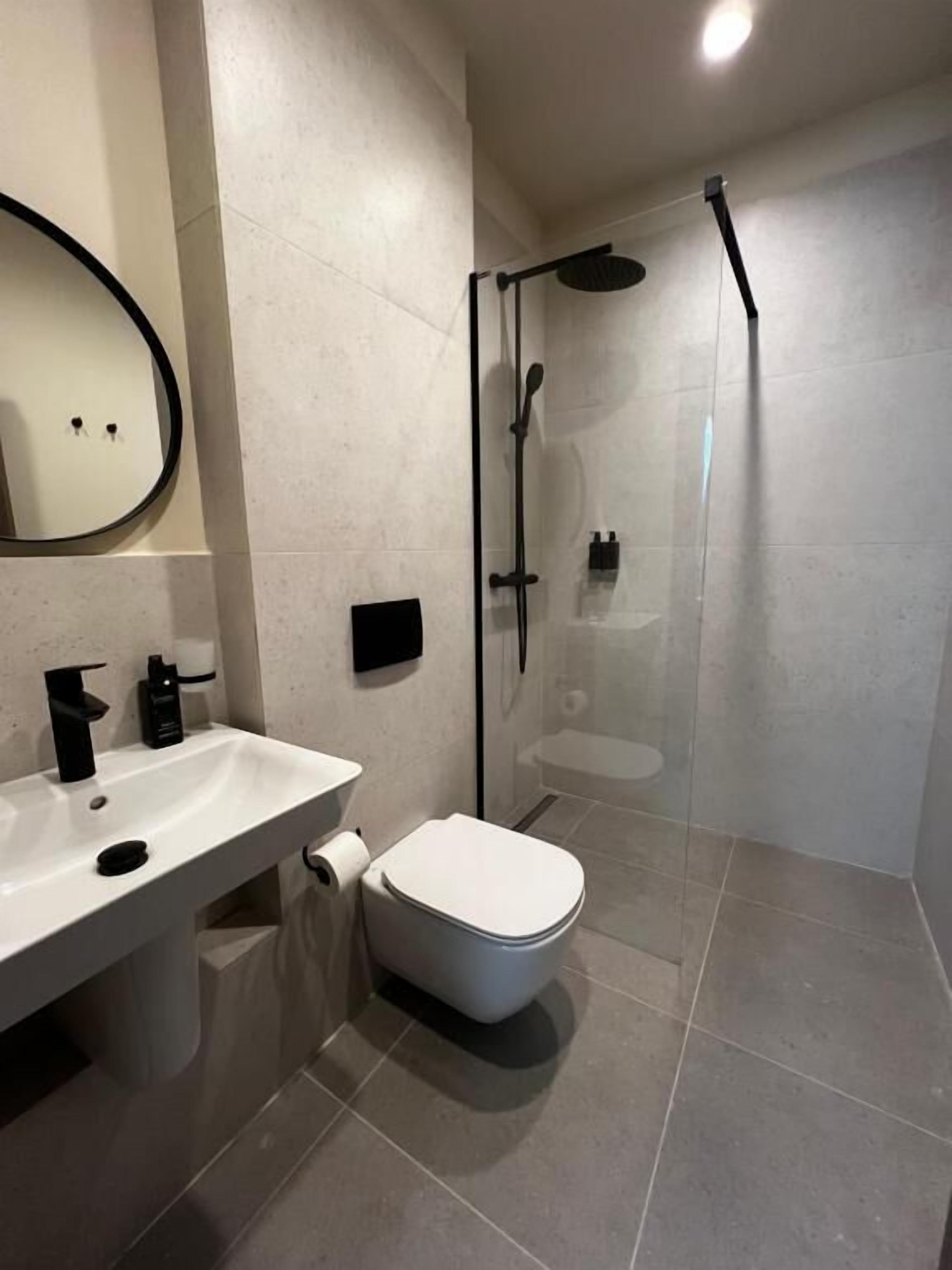A modern bathroom with a white sink, toilet, and glass-enclosed shower.