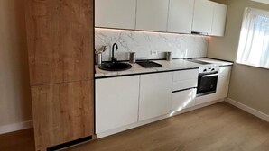 Una cocina moderna con muebles blancos, encimera negra y horno empotrado.