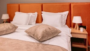 Una habitación de hotel con una cama, dos lámparas de noche y una mesita de noche con lámpara.