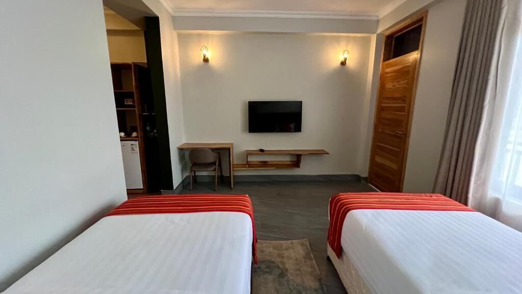 Une chambre d’hôtel avec deux lits, une télévision, un bureau et une porte en bois.
