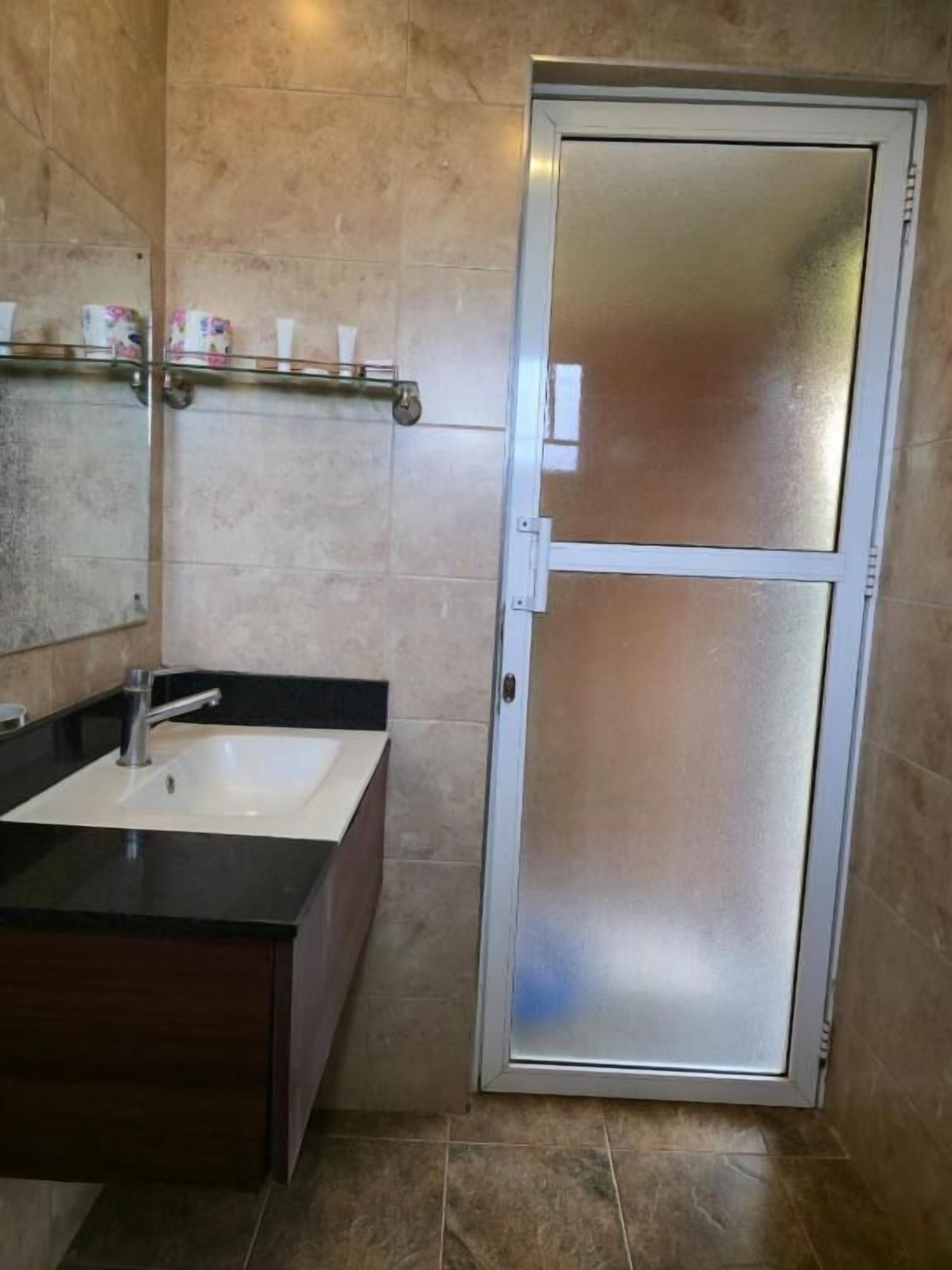 A bathroom with a glass-enclosed shower, a sink with a dark countertop, and a mirror above the sink.