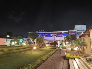 A building with a modern design, featuring a large glass facade and a well-maintained garden area with a pathway leading to the entrance. - Castle Gardens Hotel (Nairobi)