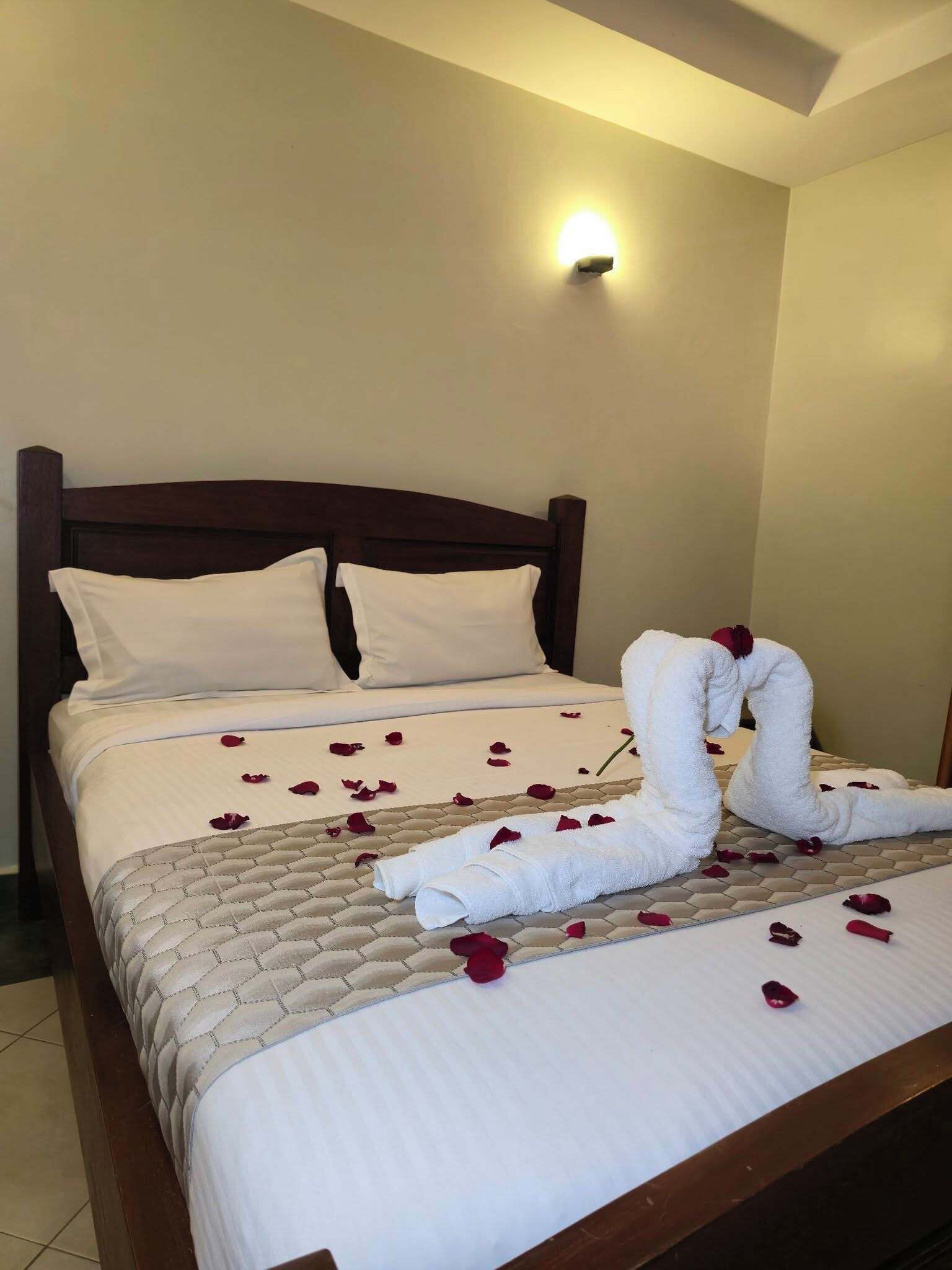 A hotel room with a neatly made bed, a headboard, and a wall-mounted light fixture.