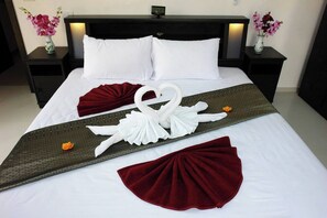 A neatly made bed with a decorative swan towel arrangement, a red throw pillow, and a patterned runner. - Siam Royal View Resort Apartment #1120 (Ko Chang)