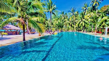 A clear blue pool surrounded by palm trees and a thatched-roof structure.