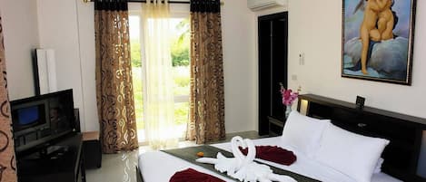 A hotel room with a bed, a TV, curtains, a painting, and a window.