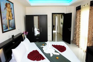 A hotel room with a bed, a wardrobe, a mirror, and a painting on the wall.