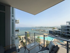 A balcony with a view of a swimming pool and a marina. - Aqua Village - Pool, Sauna, Gym, Golf Sim (Kelowna)