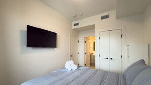 Een hotelkamer met een bed, een flatscreen televisie aan de wand en een deur naar een badkamer.