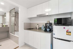 A modern kitchen with white cabinets, a built-in microwave, and a coffee maker. - 22 Rydges Plaza Esplanade with Garden Views (Cairns)