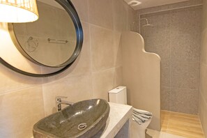 A modern bathroom with a round mirror, a vessel sink, a shower, and a toilet. - Villa in Rethymno Near Agios Pavlos Beach (Agios Vasileios)