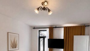 A hotel room with a bed, bedside table, TV, and a door. - Elegant Urban Retreat | Near Old Town (Bucharest)