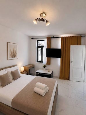 Ein Hotelzimmer mit Bett, Nachttisch, Fernseher und einer Tür.