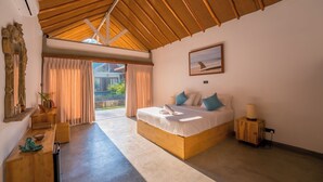 Un dormitorio con una cama grande, cabecera de madera, un cuadro de la costa y vista a un jardín por la ventana.