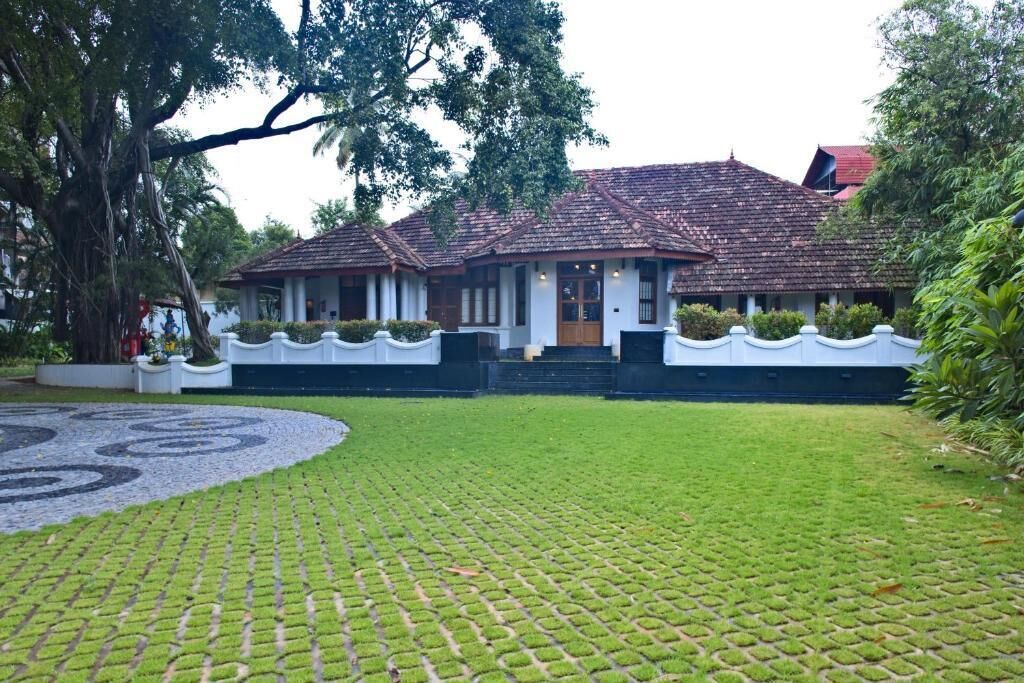 Una casa tradicional con tejado de tejas, rodeada de un césped bien cuidado y un diseño circular de piedras.