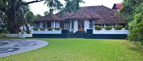 A traditional house with a tiled roof, surrounded by a well-maintained lawn and a circular stone pattern.