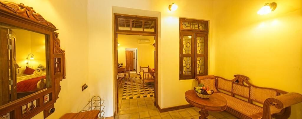 Un pasillo con un banco de madera, un espejo y una puerta que da a un comedor.