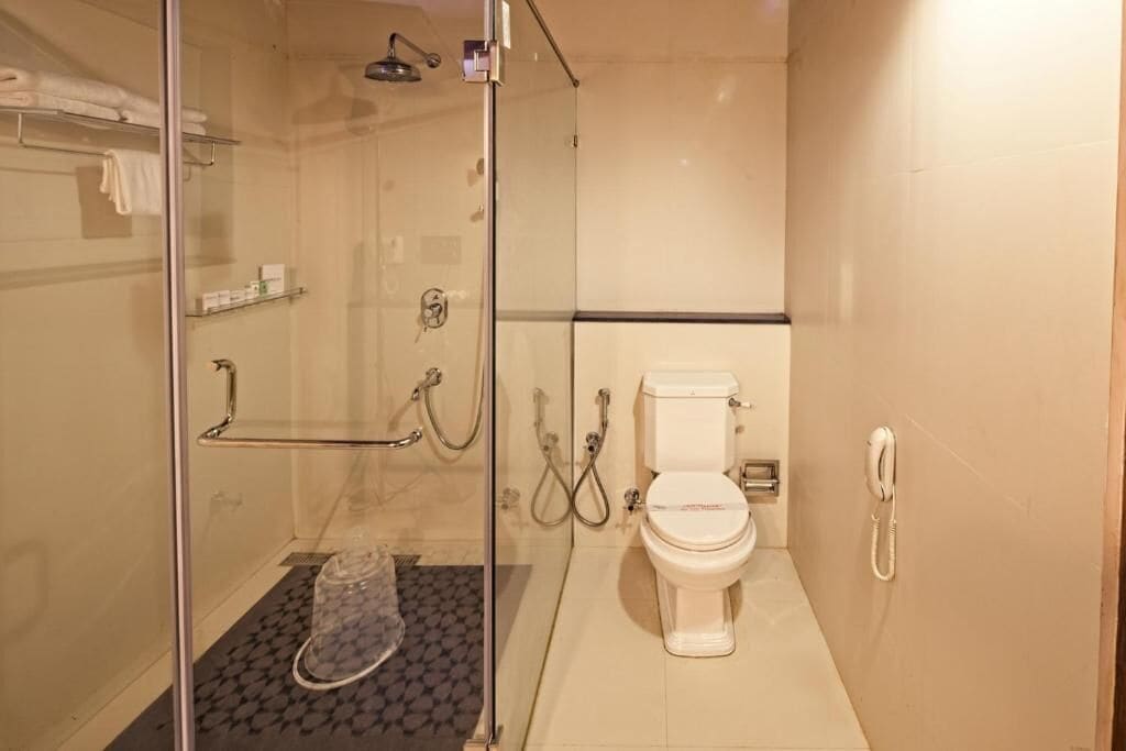 A bathroom with a glass-enclosed shower, a toilet, and a telephone.