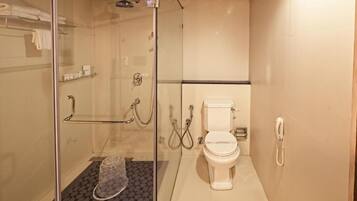 A bathroom with a glass-enclosed shower, a toilet, and a telephone.