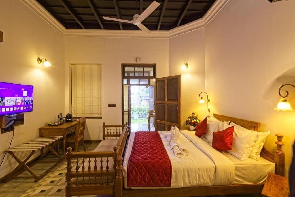 Una habitación de hotel con cama, escritorio, televisor y ventilador de techo.