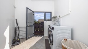 A laundry room with a washing machine, dryer, and a vacuum cleaner. - Great Short-Mid Term Stay! River Views & Games Room (Hamilton)