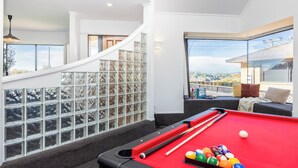 A pool table with balls and cues, a staircase with a railing, and a view of a residential area. - Great Short-Mid Term Stay! River Views & Games Room (Hamilton)