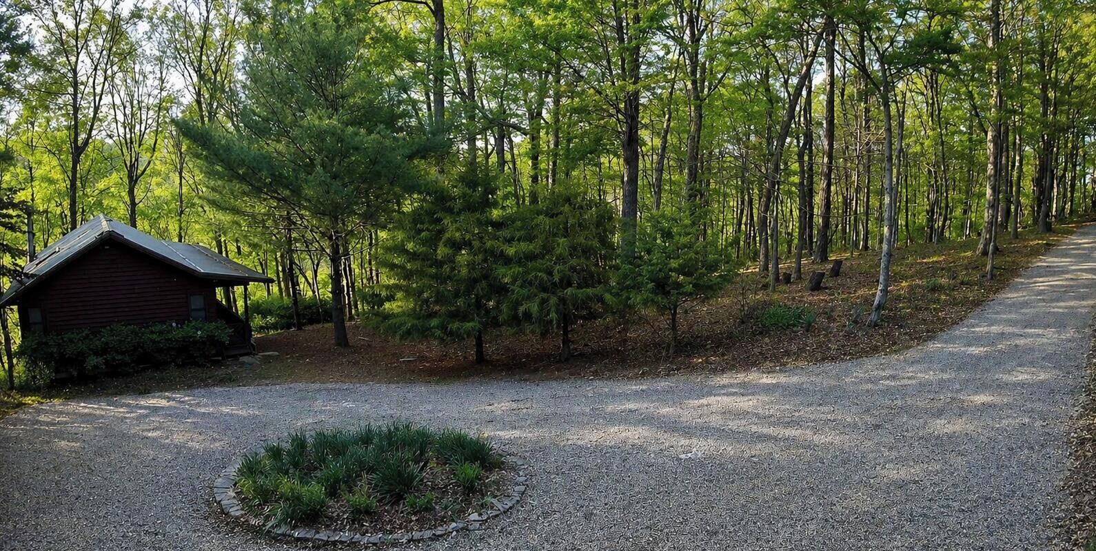 Un sendero de grava conduce a una cabaña de madera rodeada de bosque.