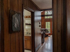 Interior de madera con un pasillo que conduce a una zona de estar y una ventana.
