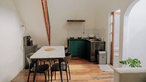 Uma cozinha compacta com área de refeições, cafeteira e um armário verde.