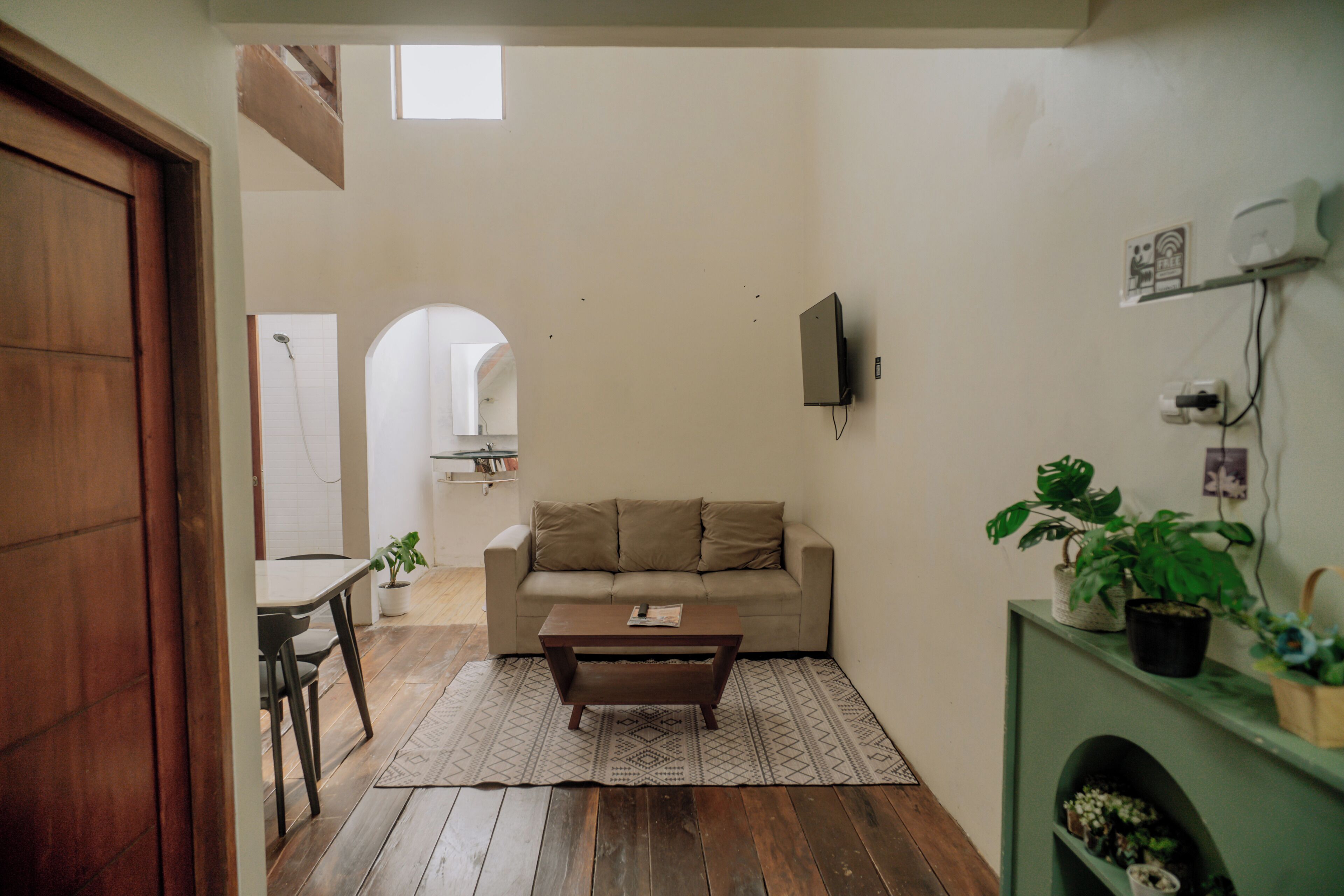 Una sala de estar con un sofá, una mesa de centro y un televisor montado en la pared.