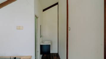 Un pasillo estrecho con suelo de madera, un lavamanos blanco y una estufa a gas.