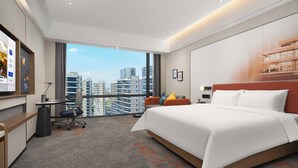 Una habitación de hotel moderna con una cama grande, un escritorio, una silla y vistas a la ciudad.
