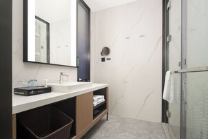 A modern bathroom with a large mirror, a sink, and a shower area.