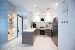 A modern kitchen with a central island, built-in appliances, and a sleek design. - Bloomfields 1BR in Al Hadeel East (Abu Dhabi)