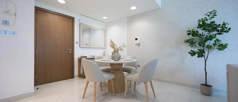 A modern dining area with a round table, four chairs, a potted plant, and a wooden door.