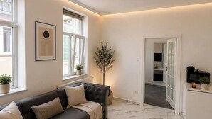 Ein modernes Wohnzimmer mit einem dunkelgrauen Sofa, einem weißen Teppich und einer Deckenleuchte.