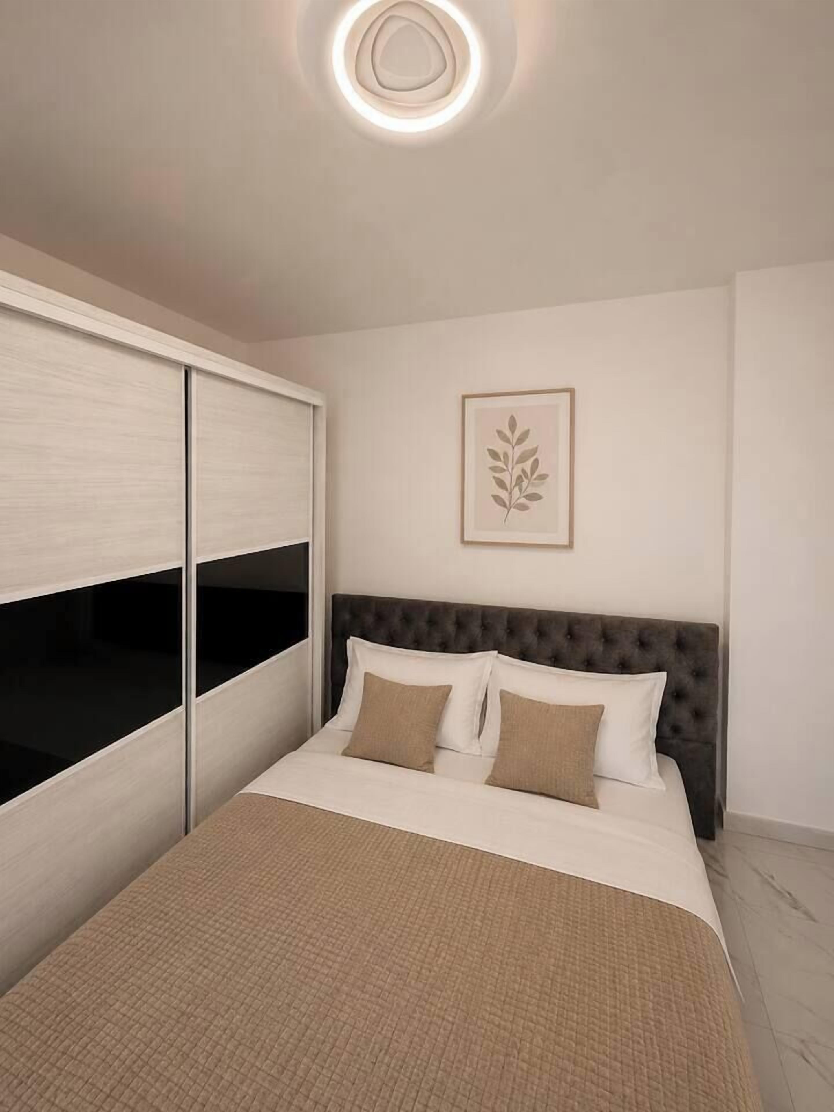 Een slaapkamer met een bed, een kledingkast en een kunstwerk in een lijst aan de muur.