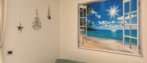 Una habitación con un sofá verde, un reloj de pared y un mural con tema de playa.