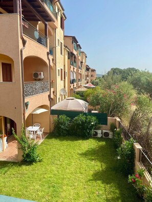 A courtyard with a lawn, outdoor furniture, and a satellite dish.