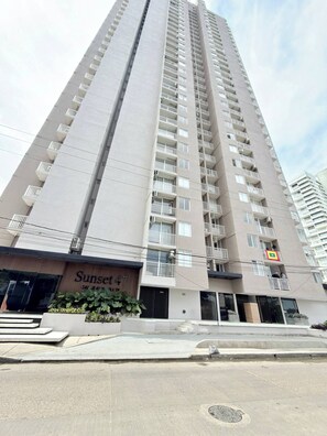 Un immeuble résidentiel de grande hauteur, doté de nombreux balcons et d’une entrée au niveau du sol.