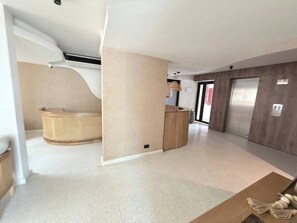 A modern interior with a reception desk, a seating area with a curved bench, and a large window.