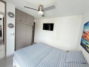 A bedroom with a bed, a ceiling fan, a wardrobe, and a painting on the wall. - Exclusive 3 Bedroom Apartment - Sunset 47 (Cartagena de Indias)