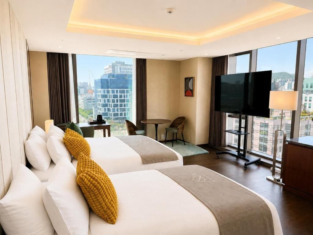 Una camera d'albergo con due letti, una televisione, una scrivania e vista sulla città.
