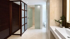 Un baño moderno con un espejo grande, un lavamanos blanco y un mamparo de vidrio.