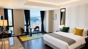 Habitación de hotel con una cama grande, un escritorio, una silla y vistas a la ciudad.