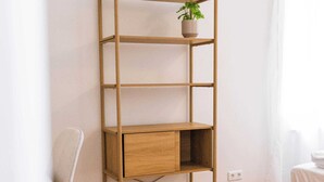 A wooden bookshelf with a plant, a desk, and a sofa in a room with wooden flooring. - Design apartment by the park with parking (Celle)