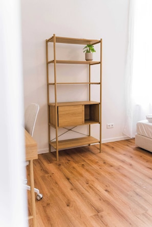 A wooden bookshelf with a plant, a desk, and a sofa in a room with wooden flooring. - Design apartment by the park with parking (Celle)