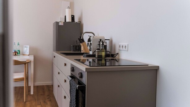 A compact kitchenette with a stove, sink, and storage drawers. - Design apartment by the park with parking (Celle)